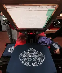 An image showing a grey colour t shirt being screen printed