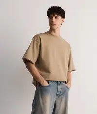A man wearing a trendy oversized t shirt in light brown colour