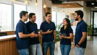 A small Indian office team in matching plain navy corporate polo uniforms talking together in a bright reception area